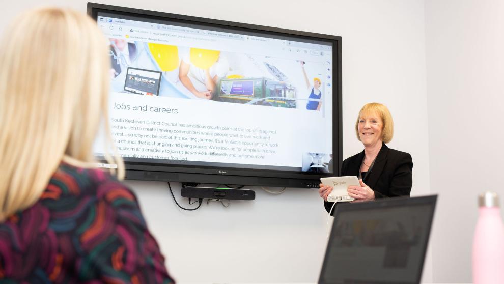 working for us picture with people in office near presentation screen