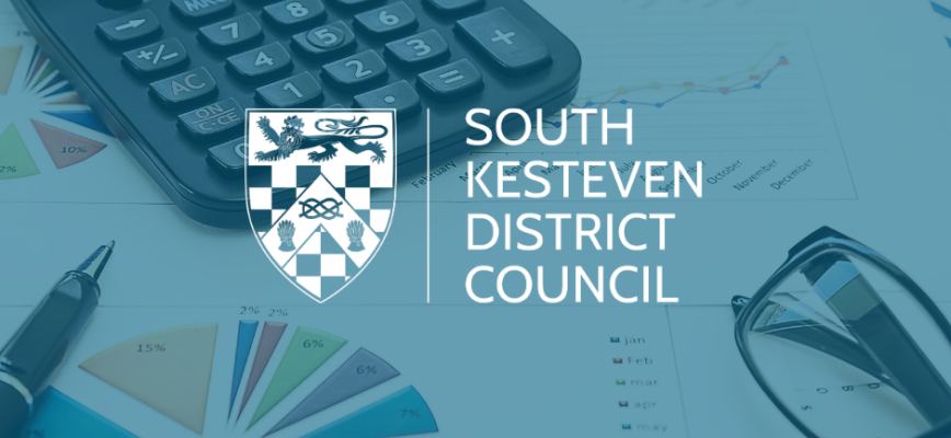 Spreadsheet, calculator and glasses. Blue screen overlaid. South Kesteven District Council logo in the centre. 