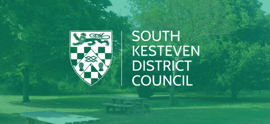 Photograph of a park with trees in the background a bench in the foreground. Green screen overlaid. South Kesteven District Council logo in the centre.